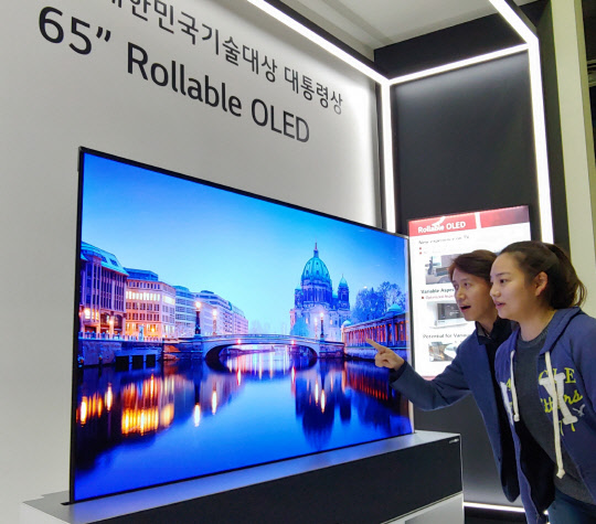 한 전시회에서 방문객이 LG디스플레이의 롤러블 OLED 패널을 구경하고 있다. <LGD 제공>